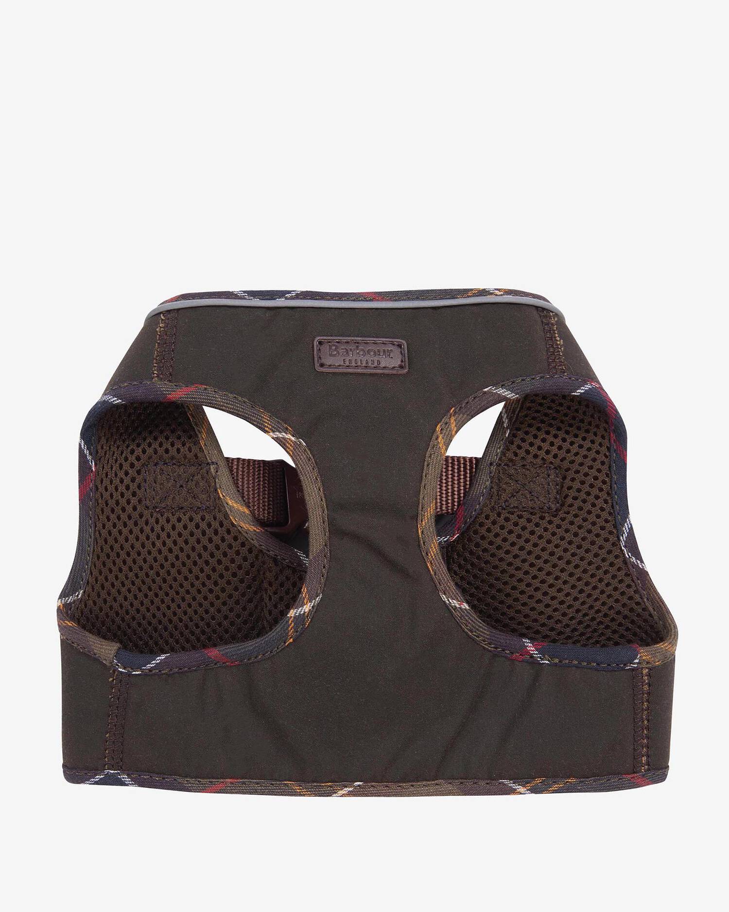 Waxed olive green step-in dog harness laid flat on a wooden surface with autumn leaves